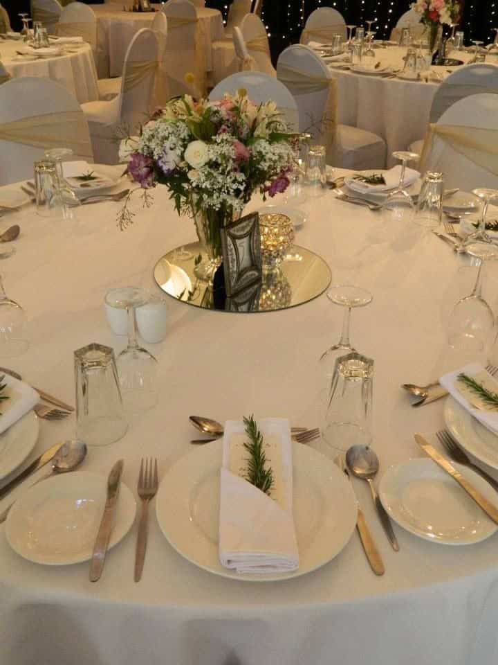 Elegant wedding table centerpiece with floral arrangement and candlelight.