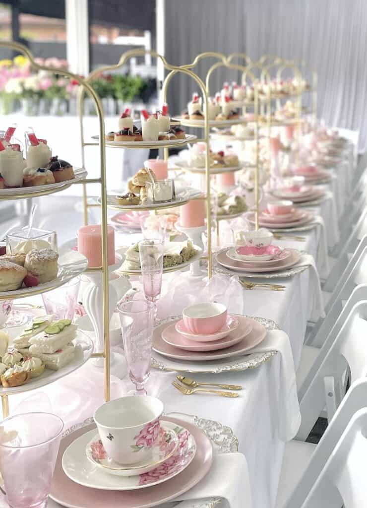 Delicate pink and white afternoon tea setup with elegant tableware and desserts.