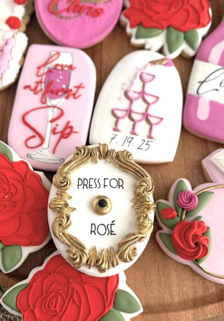 Colorful decorated cookies with rose and champagne themes for celebrations.