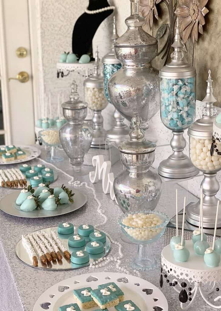 Elegant dessert table with blue and white treats and vintage glass jars.
