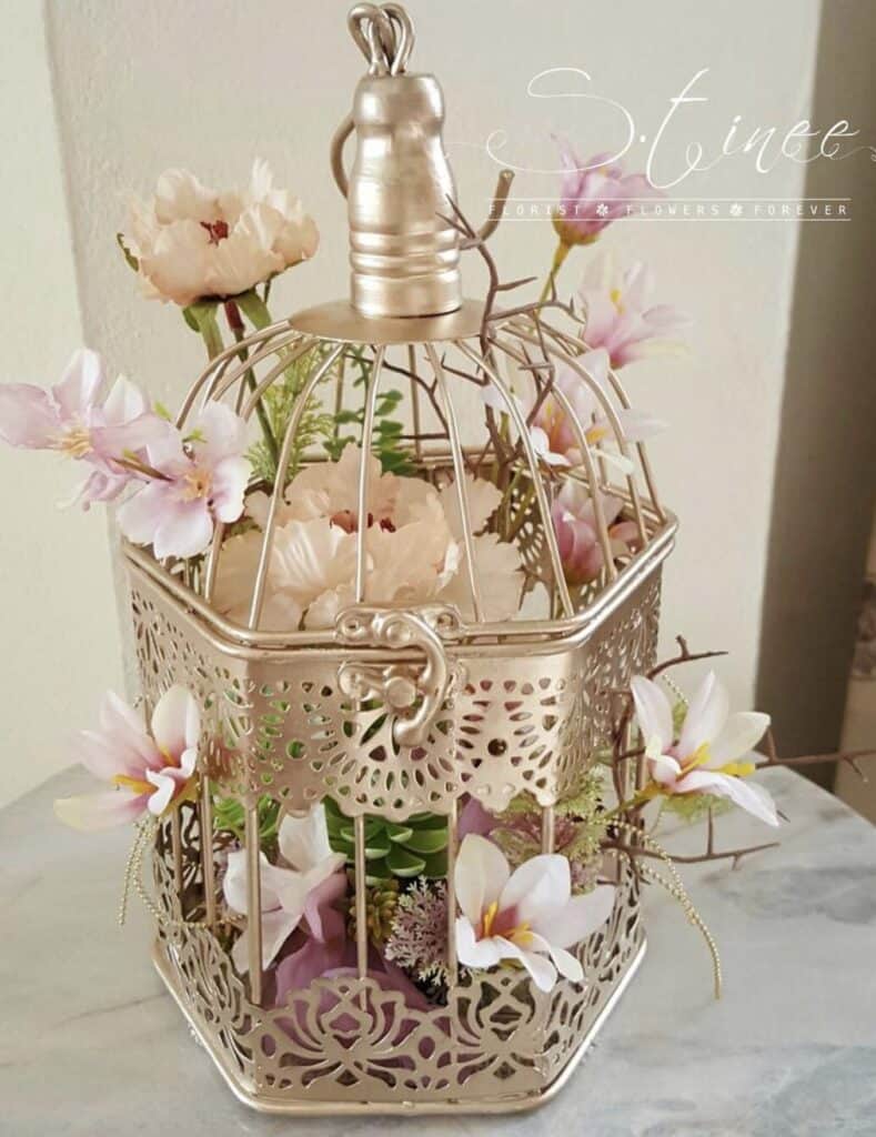 Elegant floral arrangement in vintage birdcage, pink lilies and roses, wedding decor, Confetti & Roses.