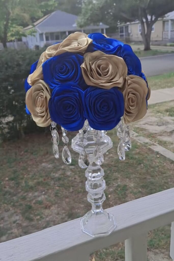 Blue and beige satin rose bouquet on a crystal stand.