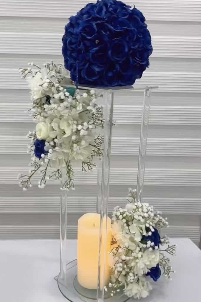 Vow floral arrangement with white and blue roses, hydrangeas, orchids on transparent stand.