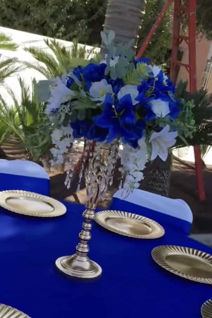 Elegant floral centerpiece with blue and white flowers on a decorated table.