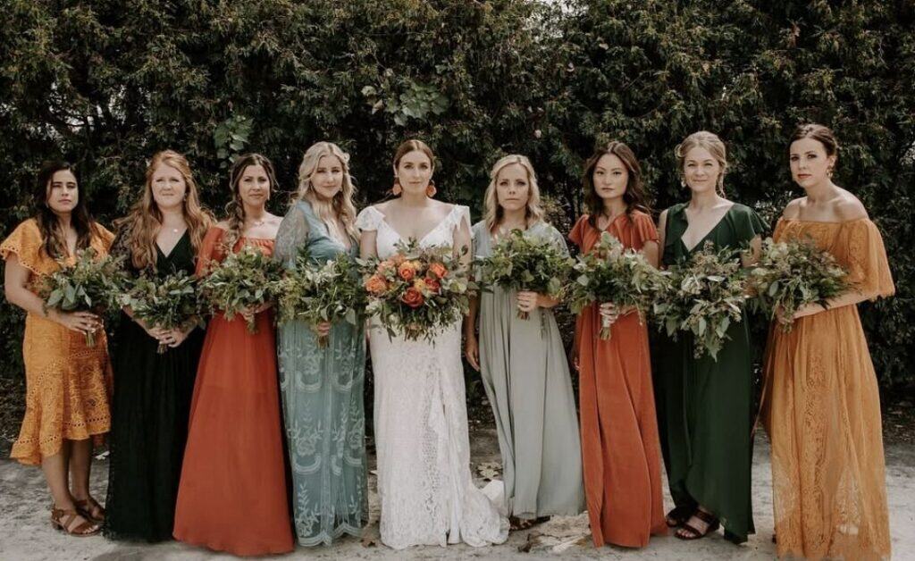 Vibrant bridesmaids holding bouquets at outdoor wedding ceremony.