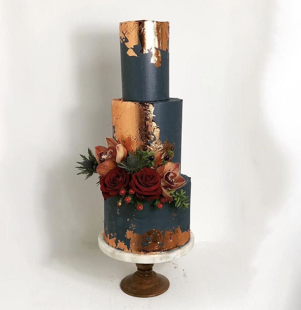 Luxurious navy blue and copper metallic wedding cake with floral accents.