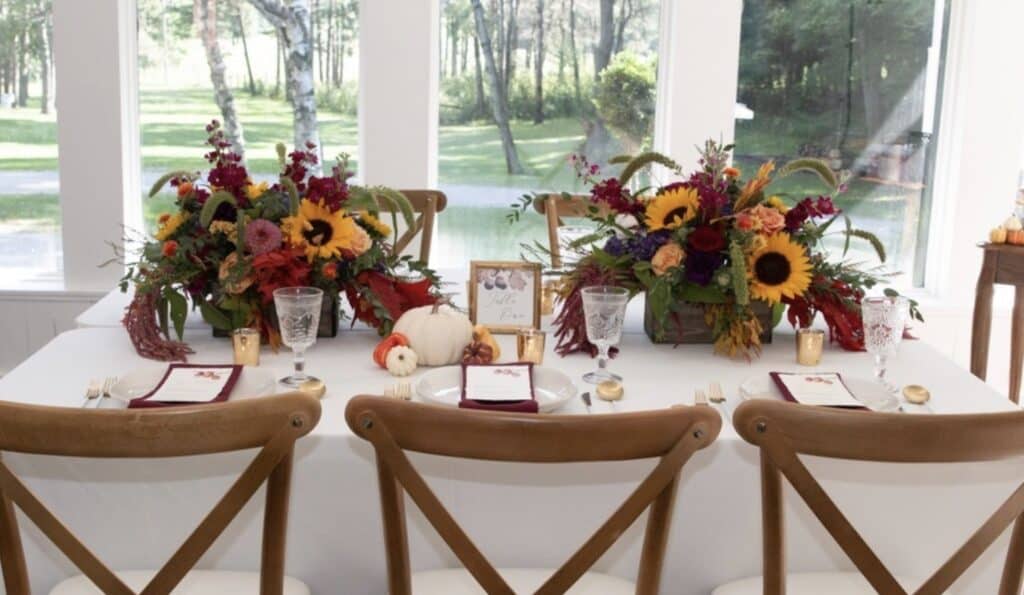 Colorful autumn floral table centerpiece with sunflowers and fall leaves.