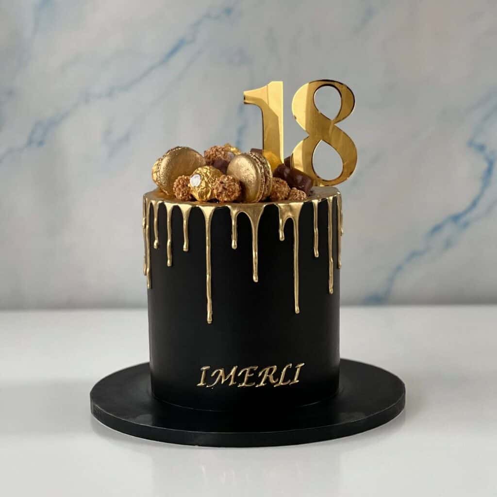 Elegant black and gold birthday cake with gold drip detail and topper.