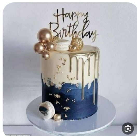 Elegant birthday cake with gold accents and metallic balloons for celebrating special occasions.
