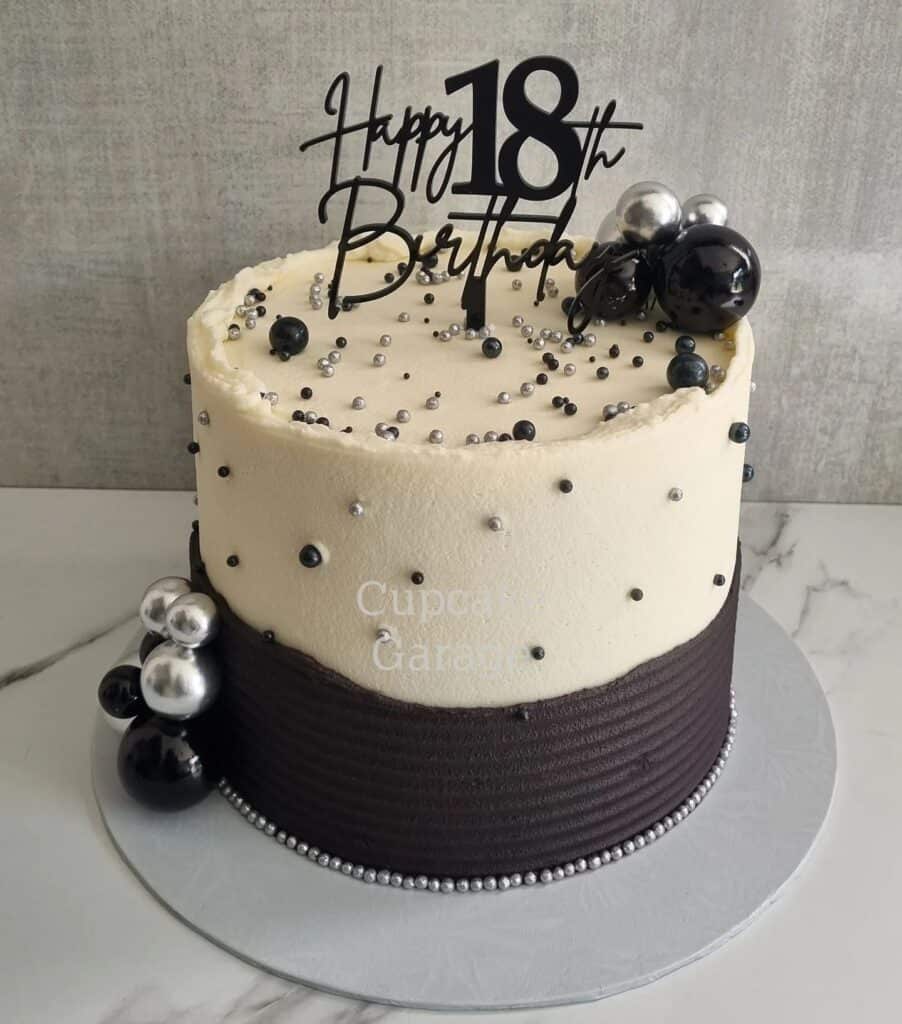 Elegant black and white birthday cake with silver and black decoration, perfect for 18th celebration.