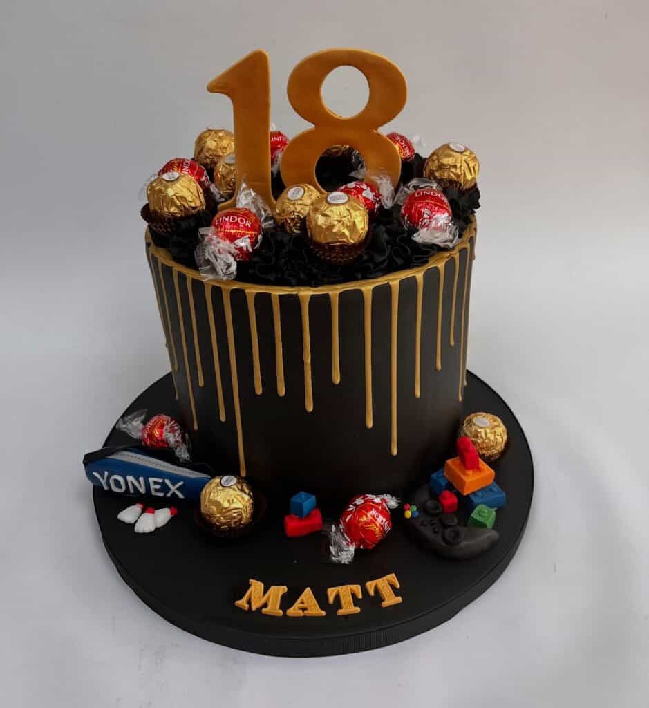 Chocolate drip cake with gold accents and candy decorations for an 18th birthday celebration.