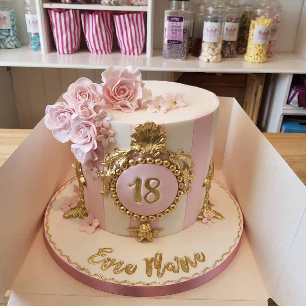 Elegant pink and gold 18th birthday cake with floral decorations and personalized message.