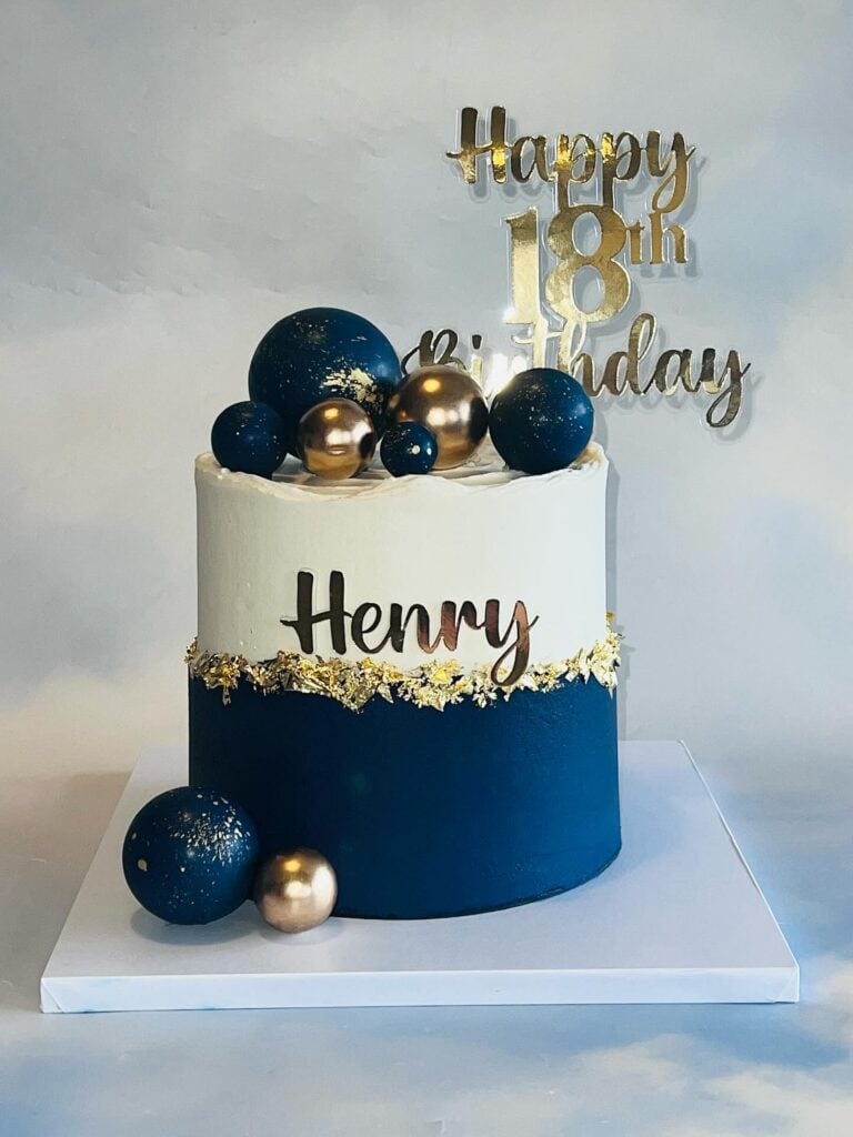 Elegant birthday cake with navy blue, white, and gold accents and personalized name "Henry".