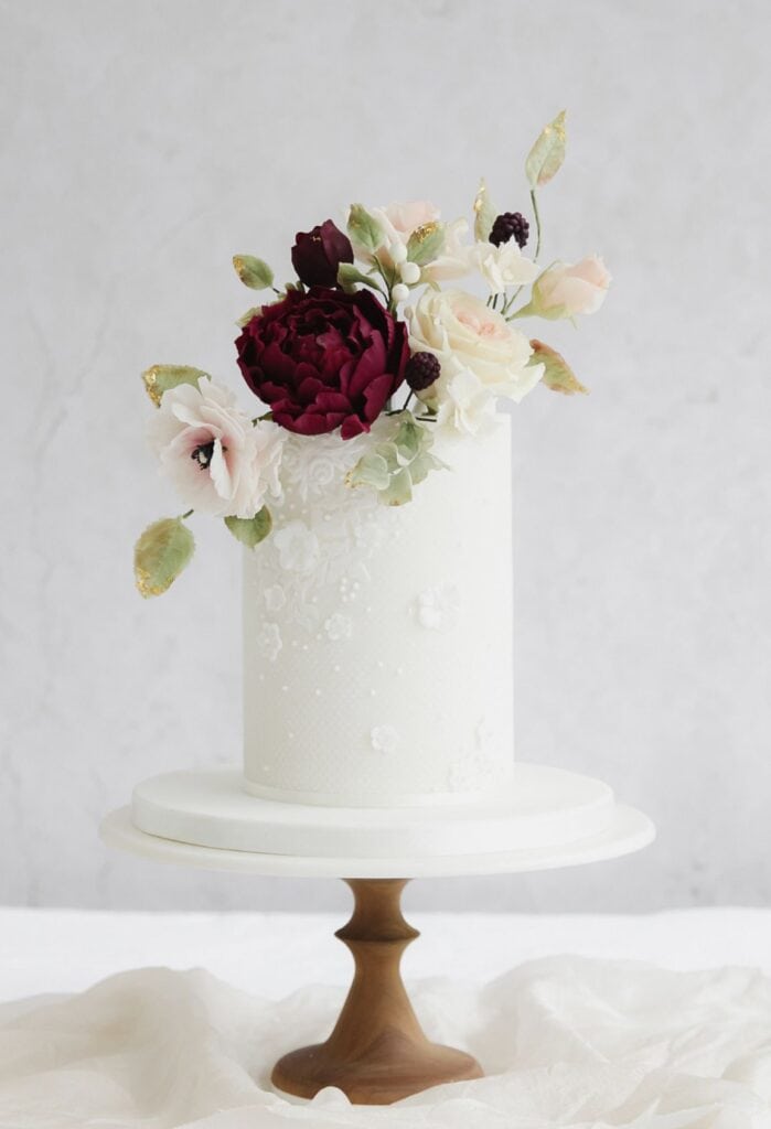 Elegant white wedding cake with floral decoration and gold accents.