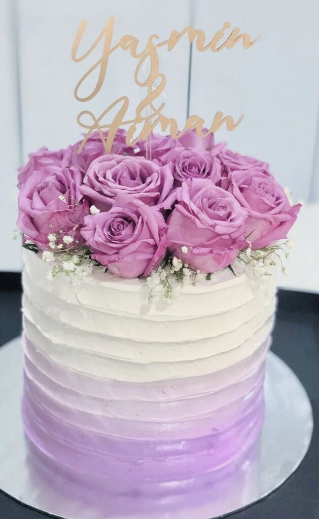 Vibrant pink roses wedding cake with floral topper and personalized acrylic cake topper.