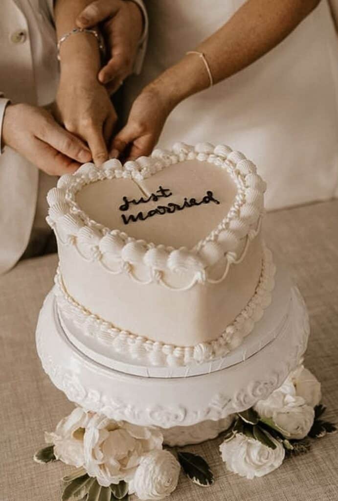 Elegant wedding cake with heart-shaped top and "Just Married" message, floral accents included.