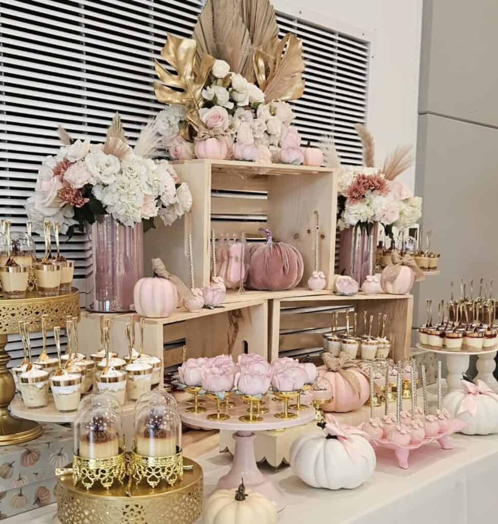 Elegant fall-themed dessert table with pastel pumpkins, floral arrangements, and gold accents.