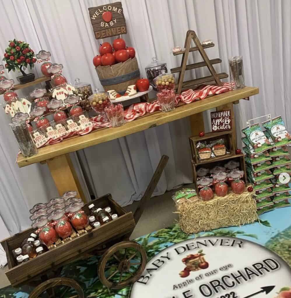 Colorful apple-themed party table with red apples and festive treats.