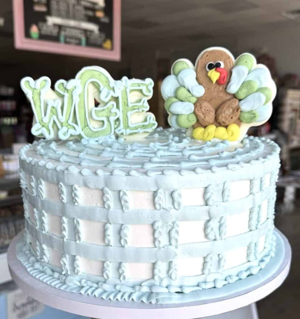 Colorful first birthday cake with "ONE" cake topper and turkey cupcake decoration.