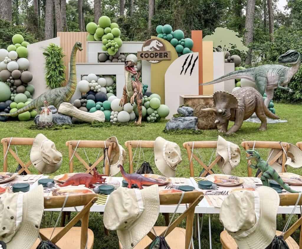 Colorful dinosaur-themed jungle party decoration with balloons and table setting.
