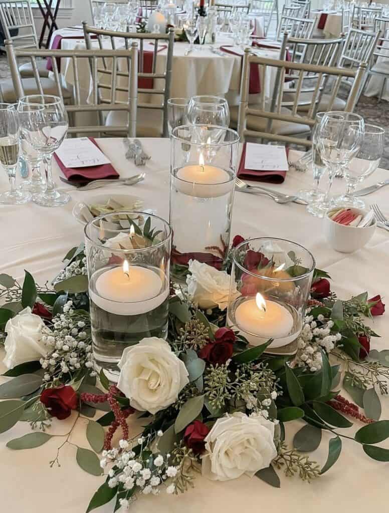Elegant wedding table centerpiece with candles, fresh roses, and floral arrangement.