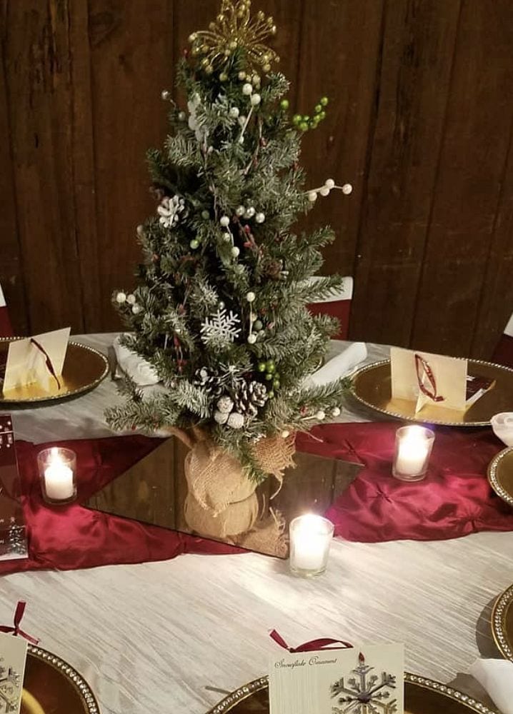 Festive Christmas table centerpiece with decorated pine tree and candles.