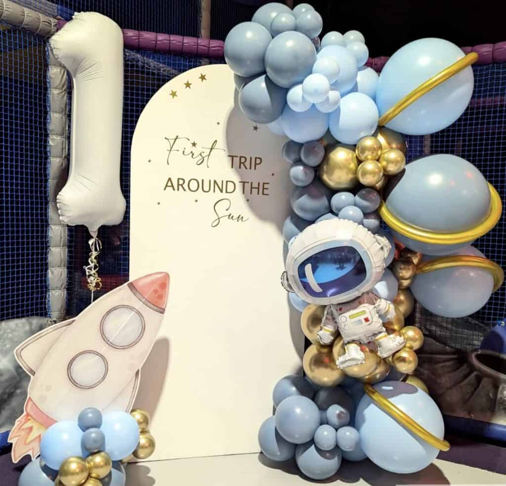 Colorful space-themed balloon decorations with astronaut and rocket for children's party.