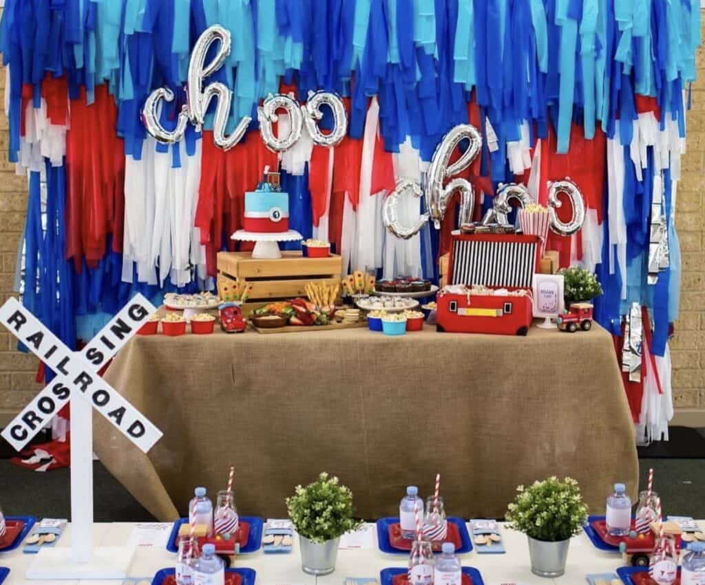 Colorful fire truck themed birthday party decoration with balloons and treats.