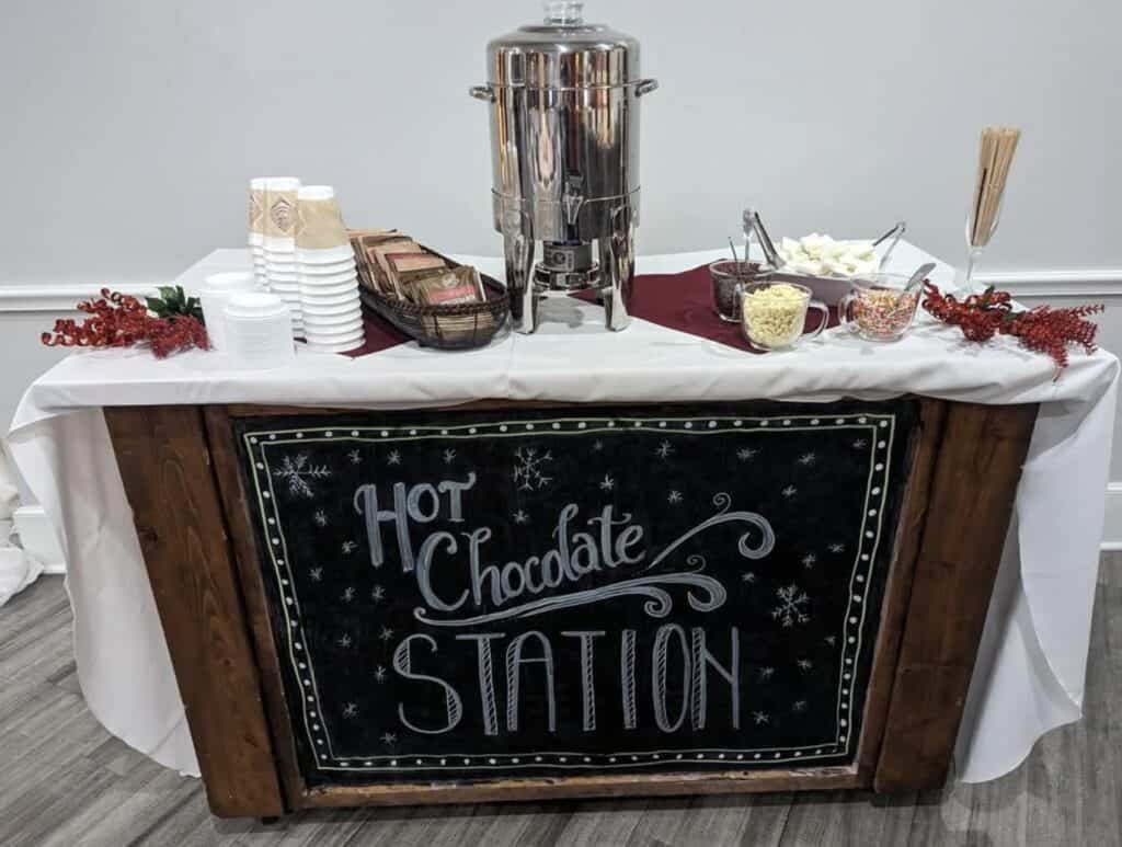 Festive hot chocolate station with toppings, cups, and snacks for winter celebration.