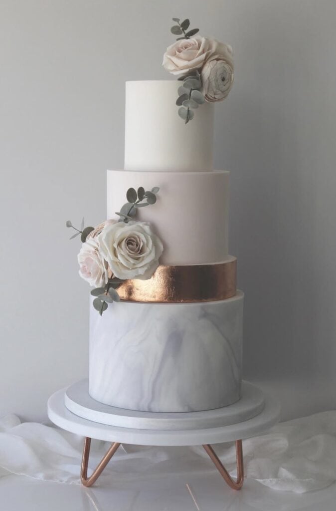Elegant white wedding cake with rose and eucalyptus decorations.