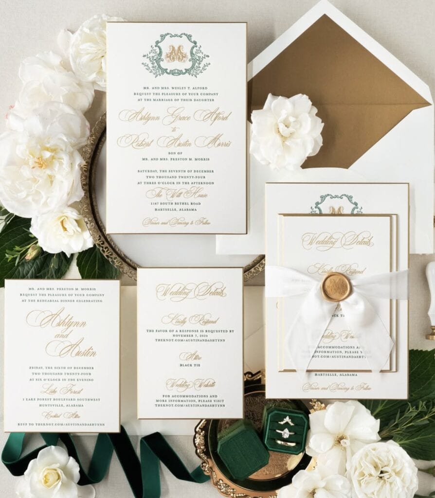 Elegant wedding invitation suite with greenery and white floral accents.
