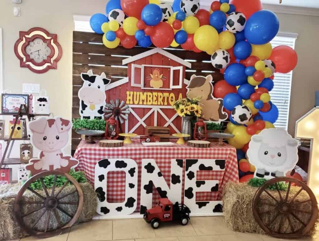 Colorful farm-themed birthday party decorations with balloons, cow, pig, horse, and sheep cutouts.