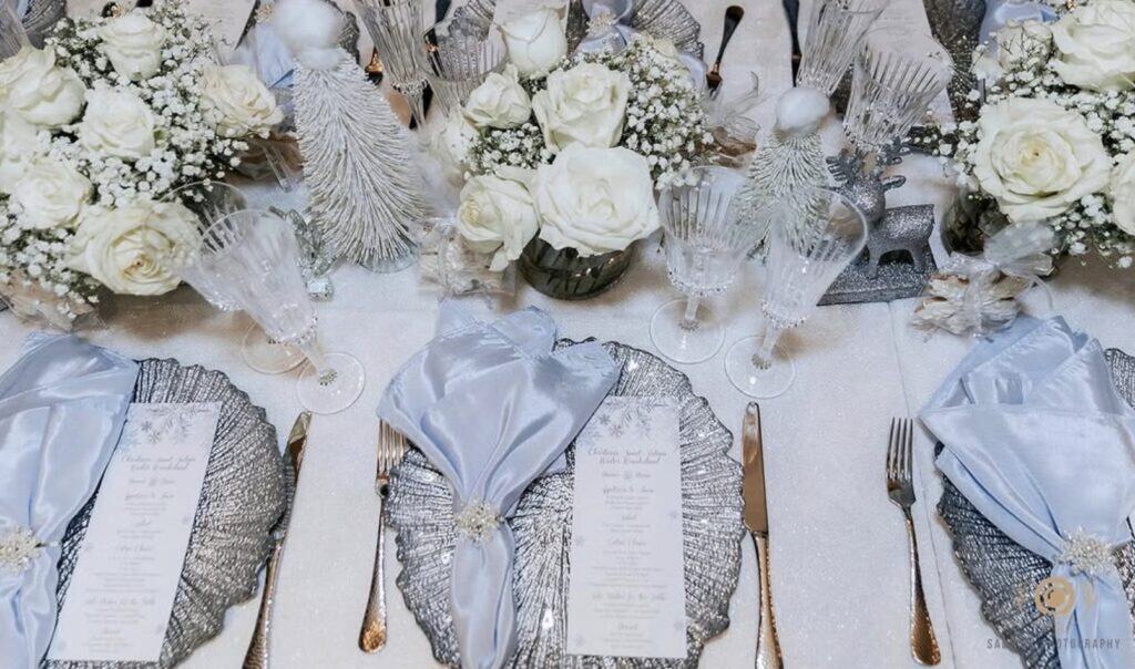 Elegant white floral wedding centerpiece with crystal glassware and silver accents.