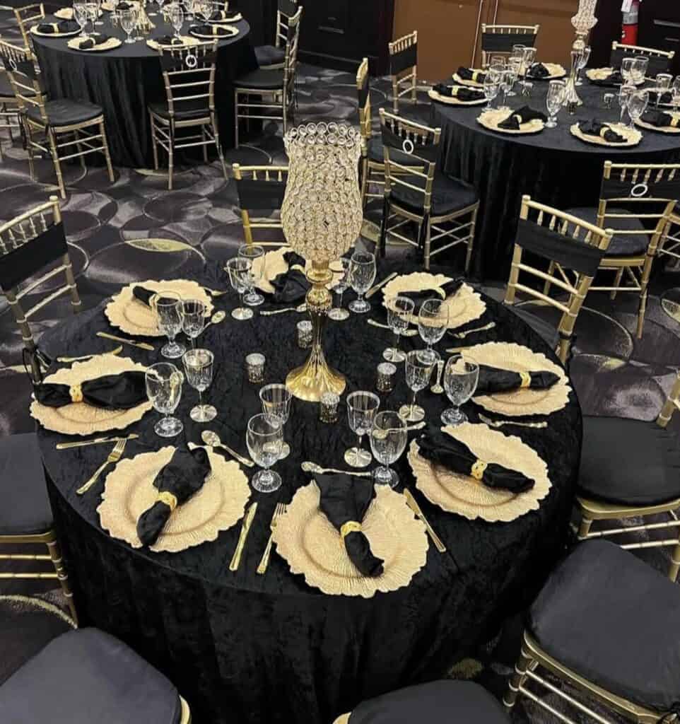 Luxurious black and gold banquet table setup with elegant decor and crystal accents.
