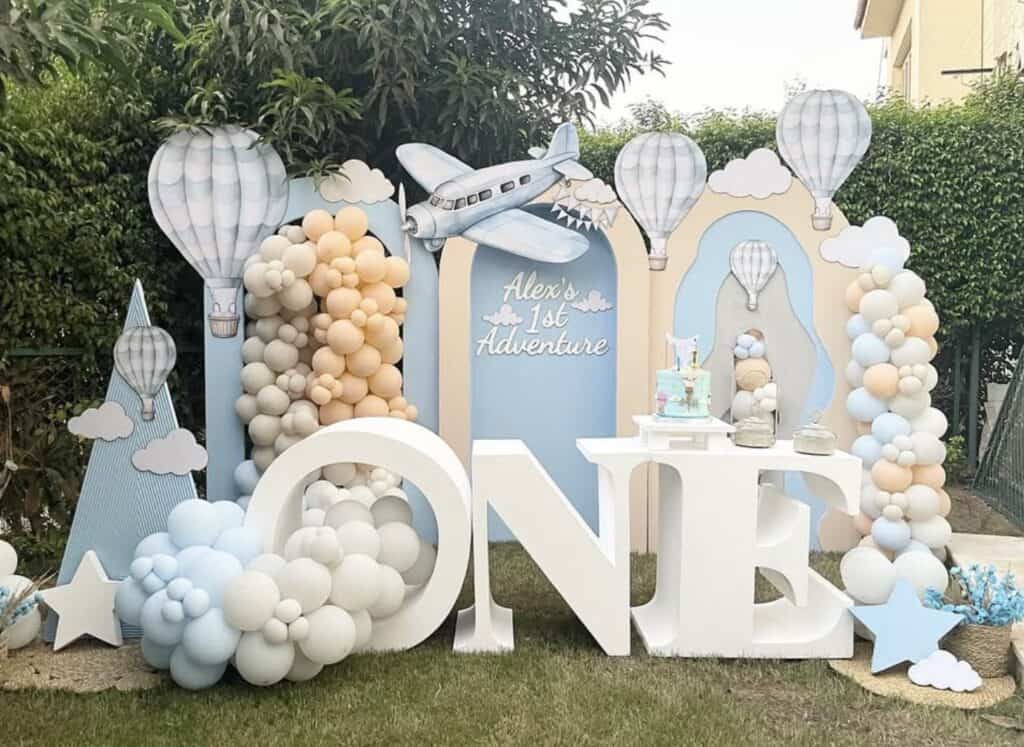 Colorful hot air balloon and airplane birthday party backdrop with balloons and clouds.