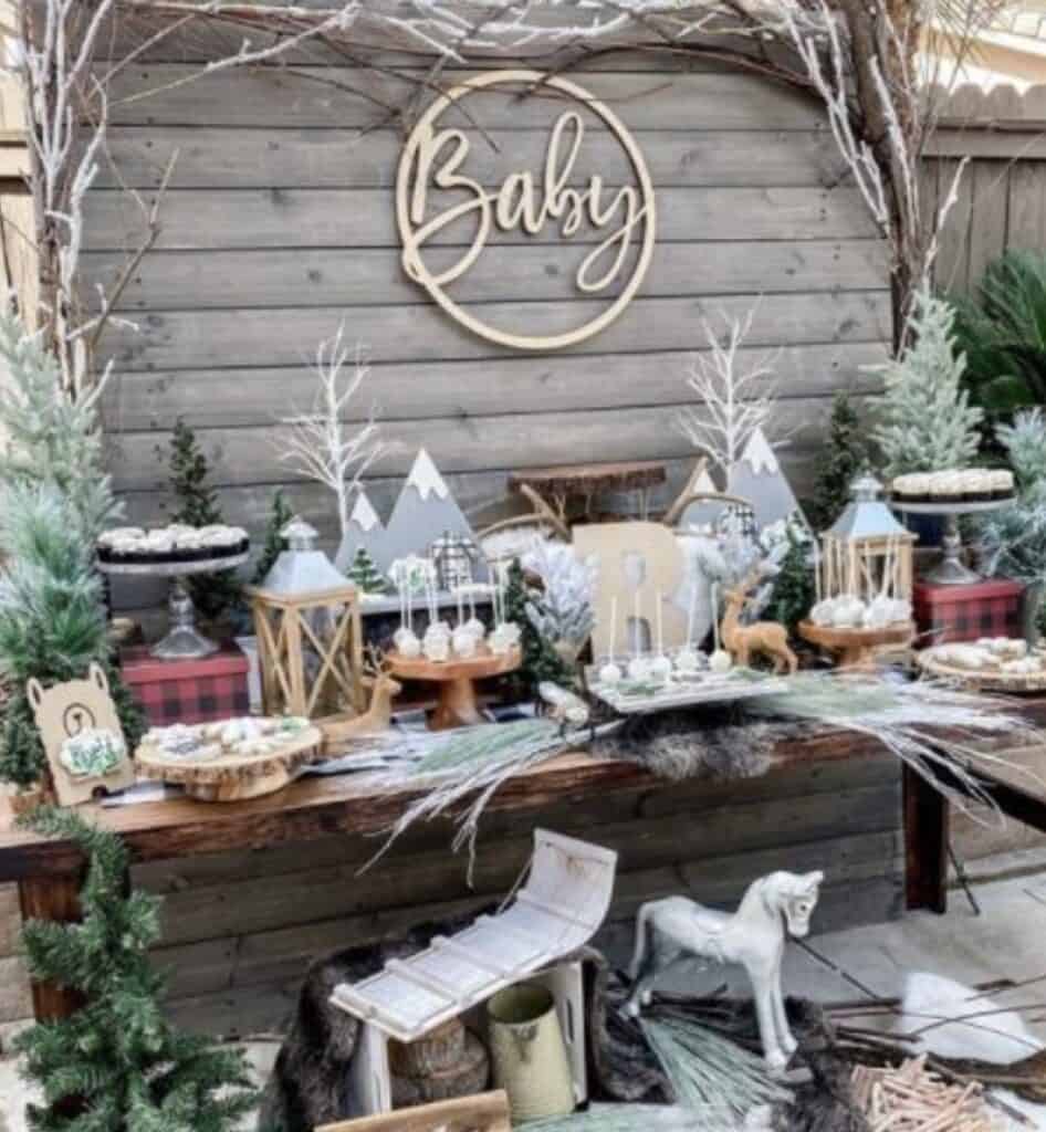 Rustic baby shower dessert table with woodland decor and winter accents.
