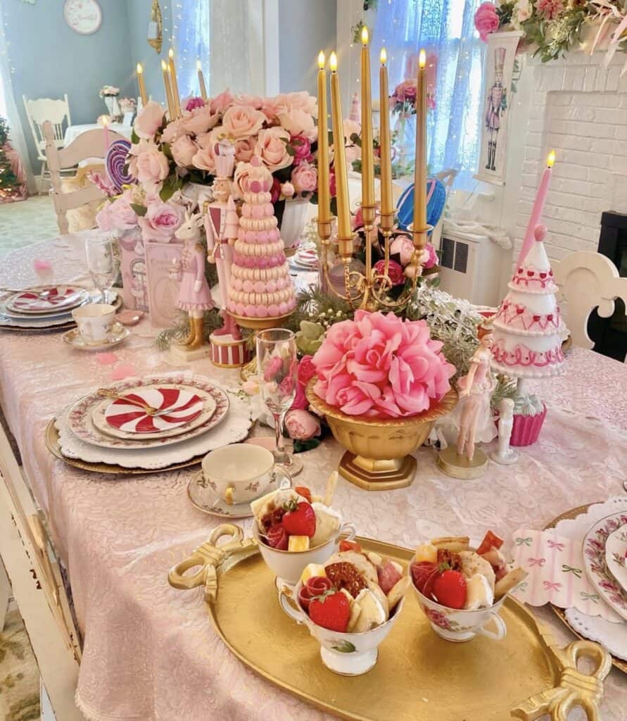 Elegant pink birthday party table with roses, desserts, and gold accents.