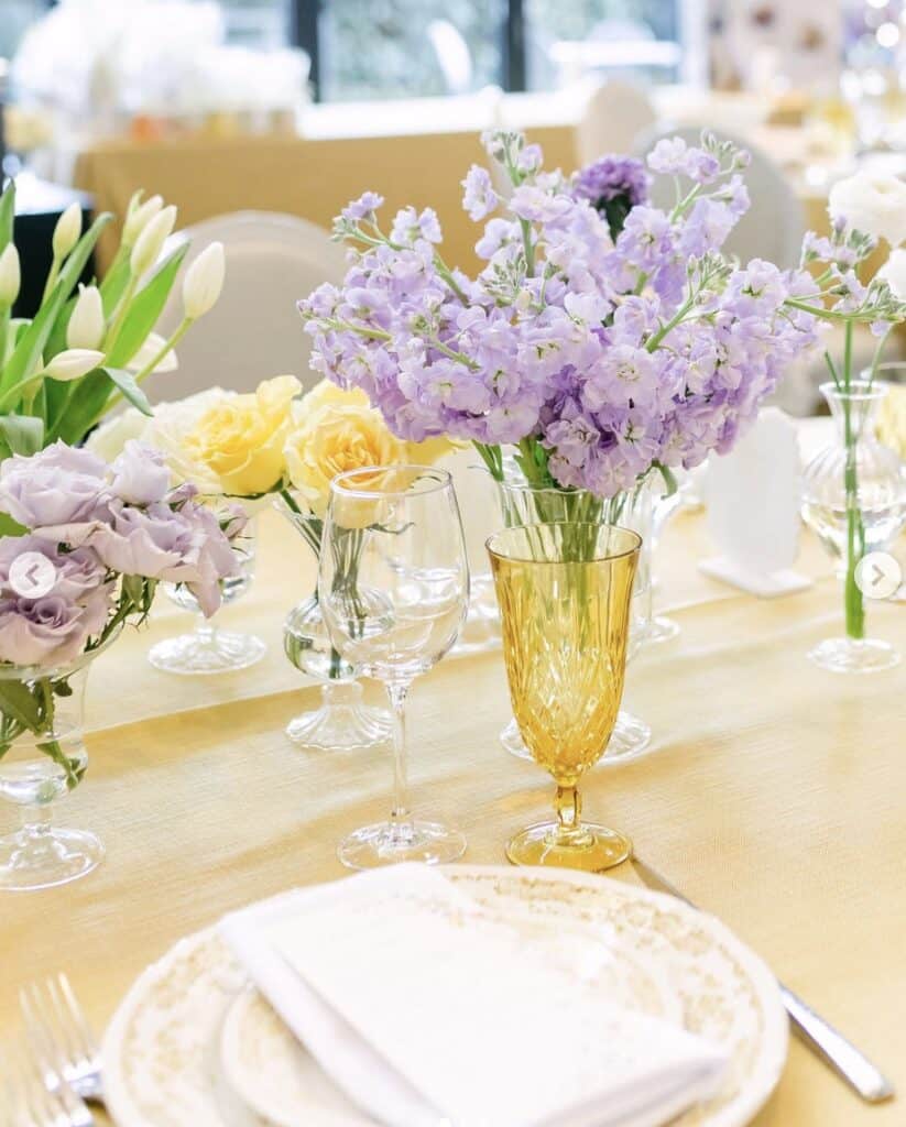 Lavender and yellow floral centerpiece for elegant event table setting.