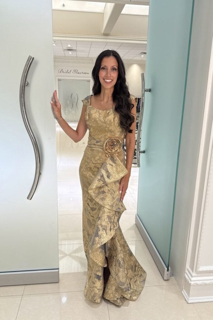 Elegant woman in gold formal gown at bridal showroom.