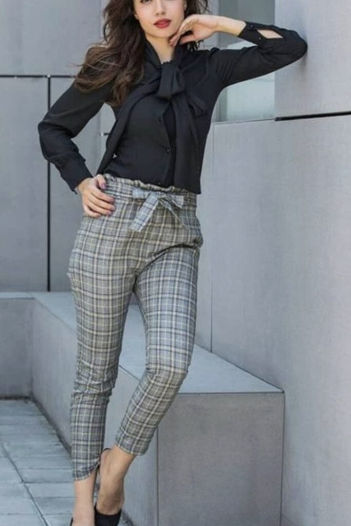 Stylish woman in plaid pants and black blouse, modern fashion look.