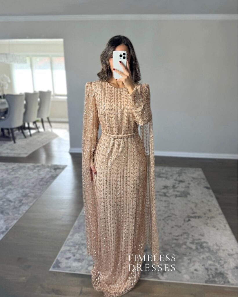 Elegant champagne evening gown with intricate beadwork and long sleeves.