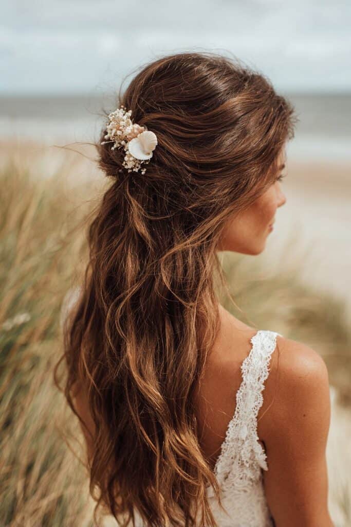 Beach wedding hair with floral hairpiece and loose waves.