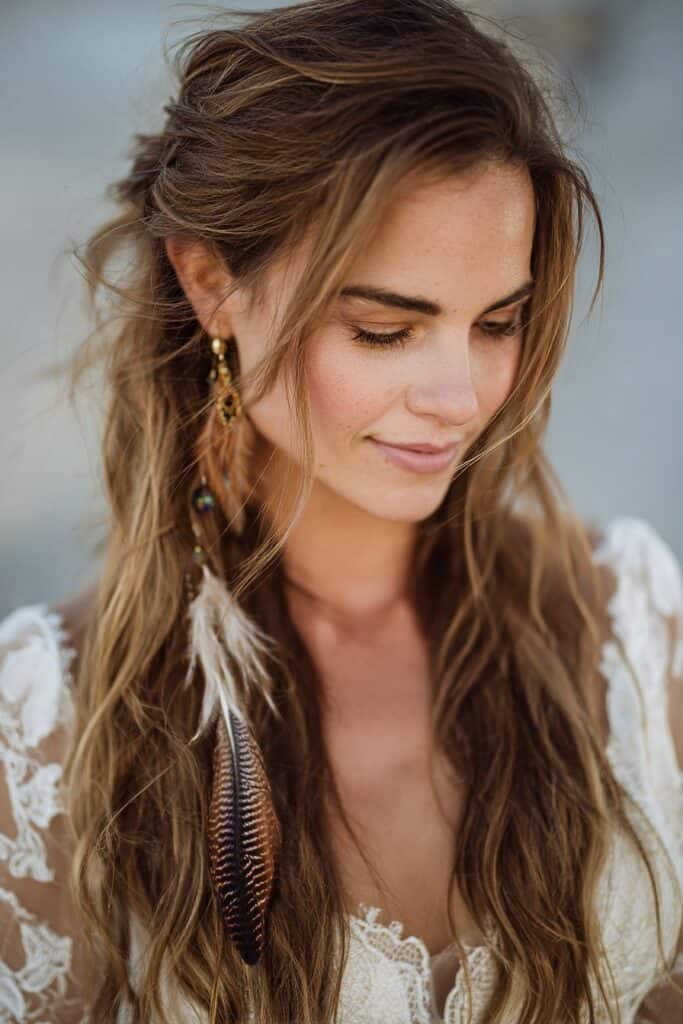 Soft boho-inspired hairstyle with feather accessory for a natural, feminine look.