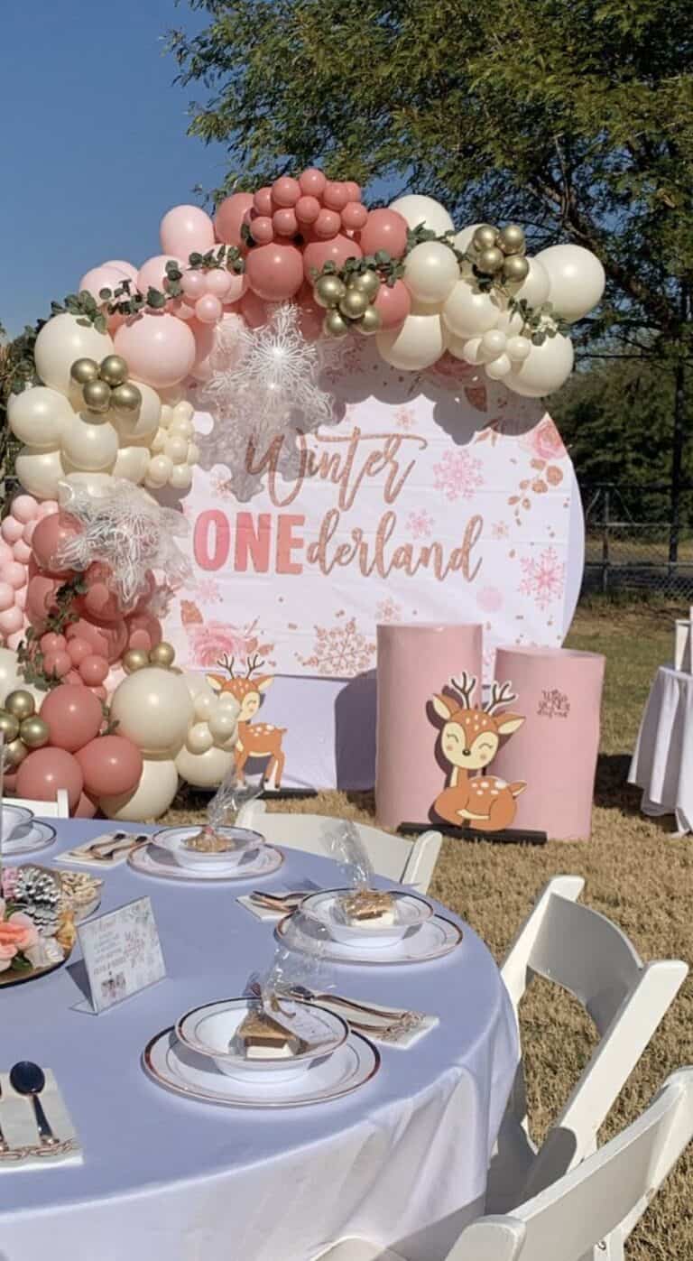 Balloon arch with pink, white, and gold balloons for winter wonderland party.