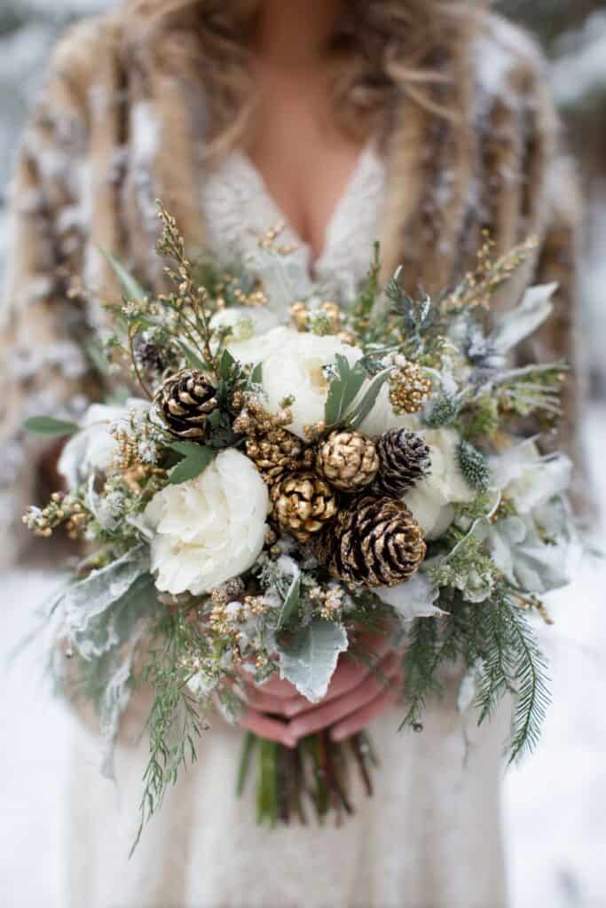 Pinecone bouquet with white flowers and greenery, winter wedding floral arrangement.