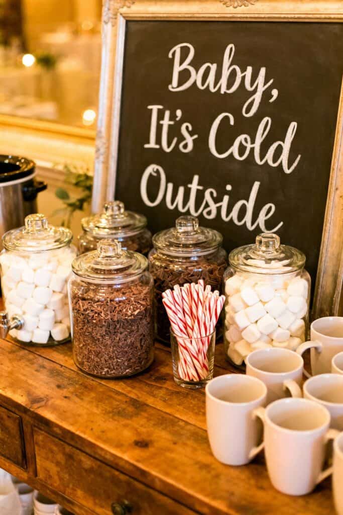 Colorful candy bar with marshmallows, chocolate shavings, and striped straws at baby shower.
