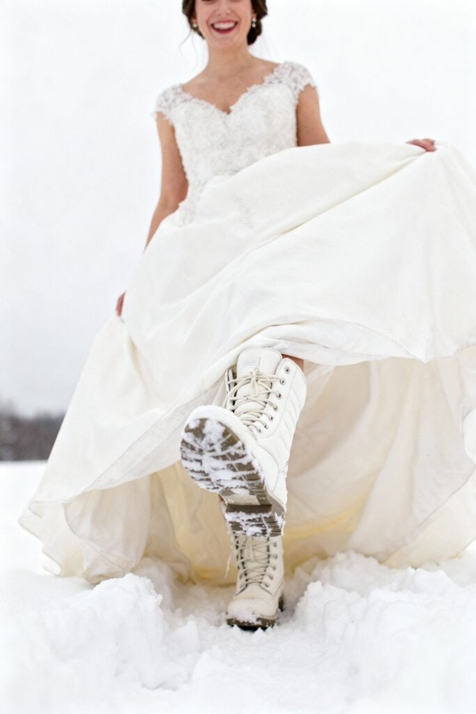 White wedding dress with lace details and snow boots in winter snow field.