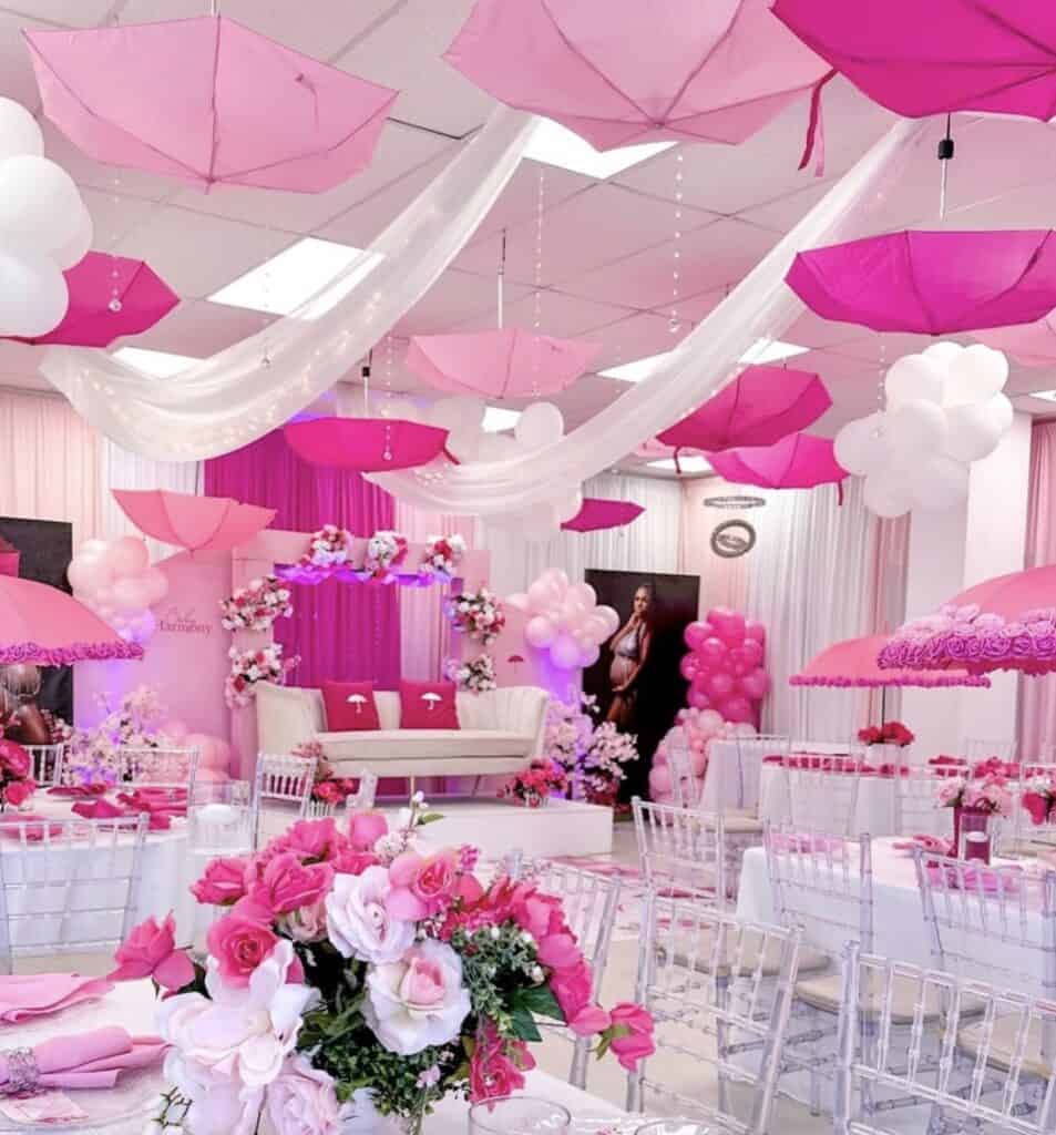 Bright pink and white balloon decorated baby shower celebration with floral centerpieces.