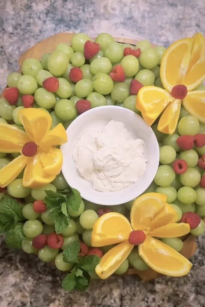 Fresh green grapes and raspberries with lemon slices and whipped cream.