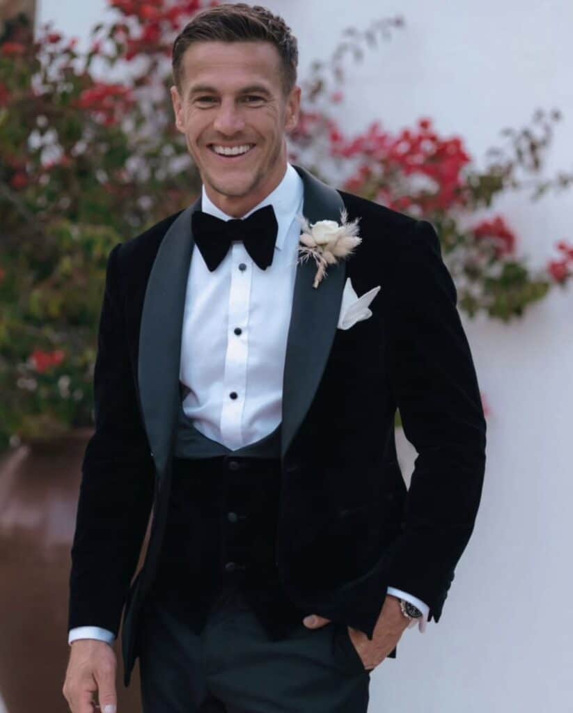 Elegant groom in tuxedo with boutonniere at wedding celebration.